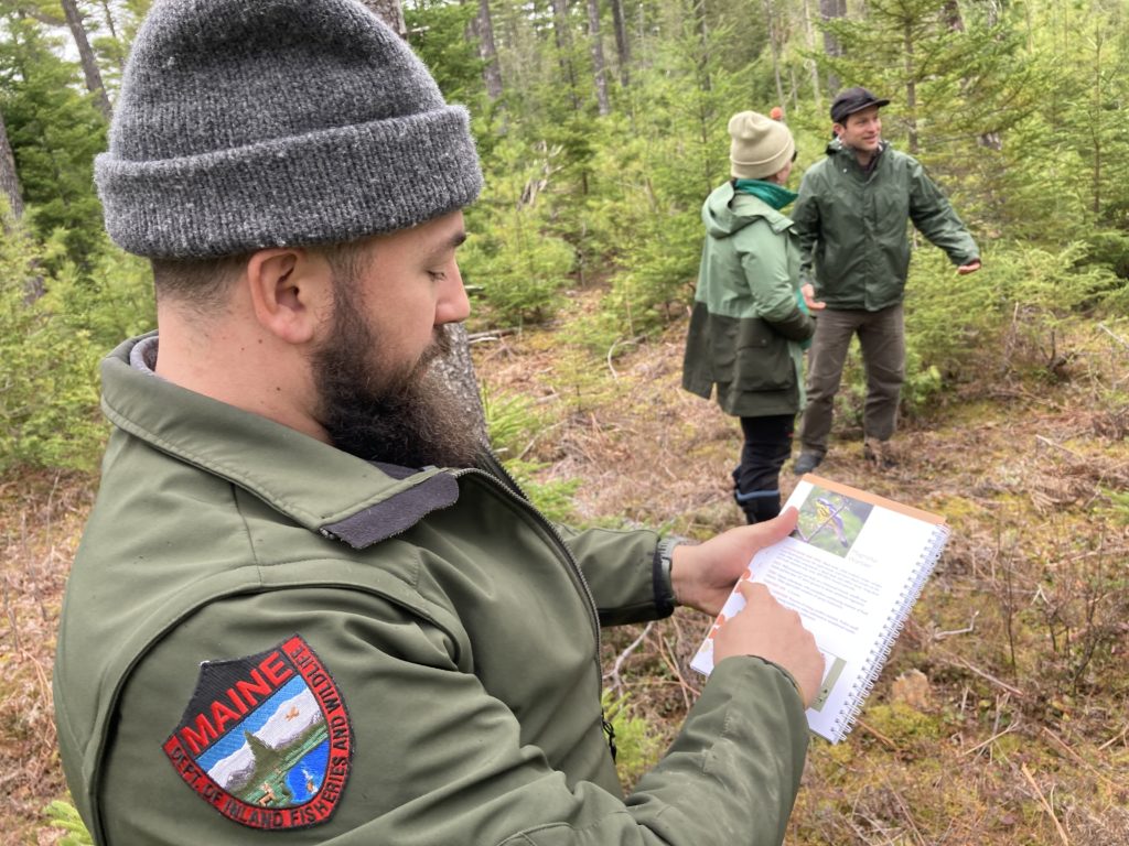 Joe Roy, ME Dept of Inland Fisheries and Wildlife, pointing to the Magnolia Warbler page in the Forestry for Maine Birds guide. 